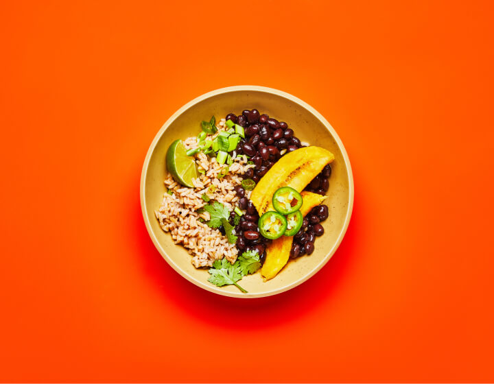 A Black Bean & Plantain Grain Bowl on an orange table