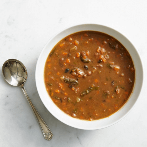 BEANS & GREANS SOUP ON MARBLE BACKGROUND WITH A SPOON.