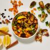 Roasted Brussels Sprouts Bowl surrounded by its ingredients: Brussels sprouts, butternut squash, walnuts, currants, lemon, and cinnamon