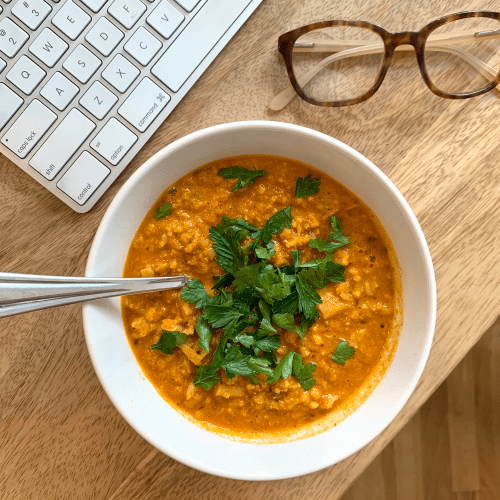 Cauliflower Tikka Soup WITH SPOON ON WOODEN BACKGROUND WITH GLASSES AND KEYBOARD. 