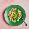 Creamy Mushroom and Spinach Noodles in a bowl on a pink surface with a fork in them.