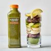 Green Matcha smoothie next to a glass cup filled with green matcha, dates, bananas, avocado, and lemon on a white background.