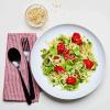 Kale Pesto Noodles on a plate with a napkin, utensils, and small dish of plant-based parmesan. 