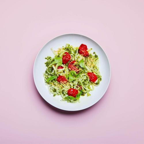 Kale Pesto Noodles in a dish on a pink background.