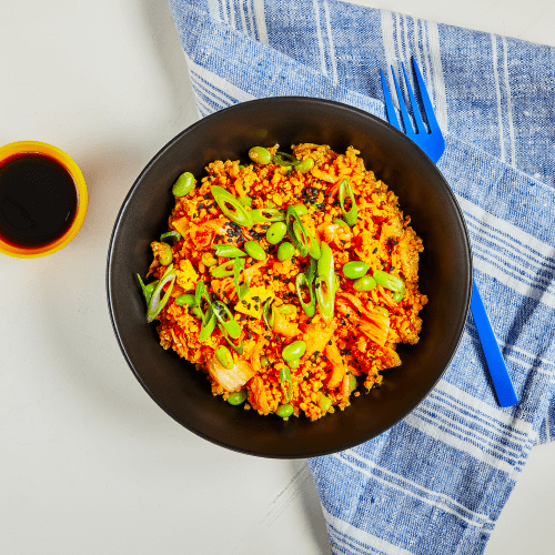 Kimchi Bowl with blue fork and napkin.