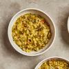 Two white bowls of Masala Khichri Soup on a concrete background.