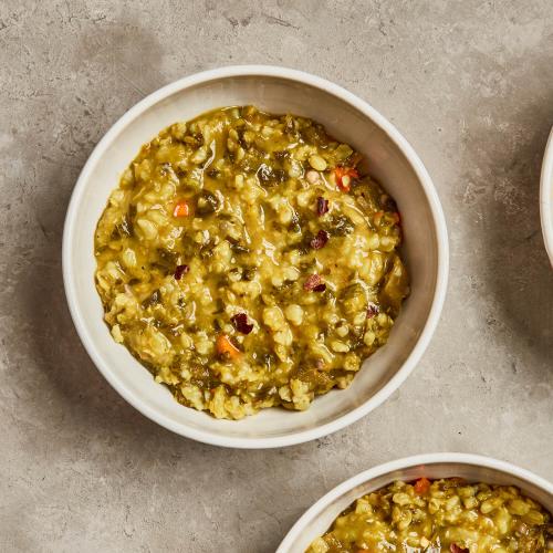 Two white bowls of Masala Khichri Soup on a concrete background.