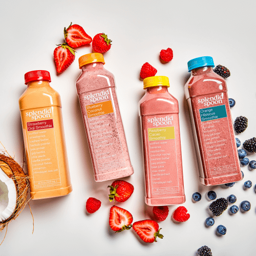 Coconut, strawberry goji in bottle, chocolate cherry in bottle, raspberry cacao in bottle, orange hibiscus in bottle with strawberries, raspberries, blueberries & blackberries on a white background.  