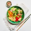 Tangy Ginger Noodles in a dish on a white background with a napkin, chopsticks, and a dish of almonds.